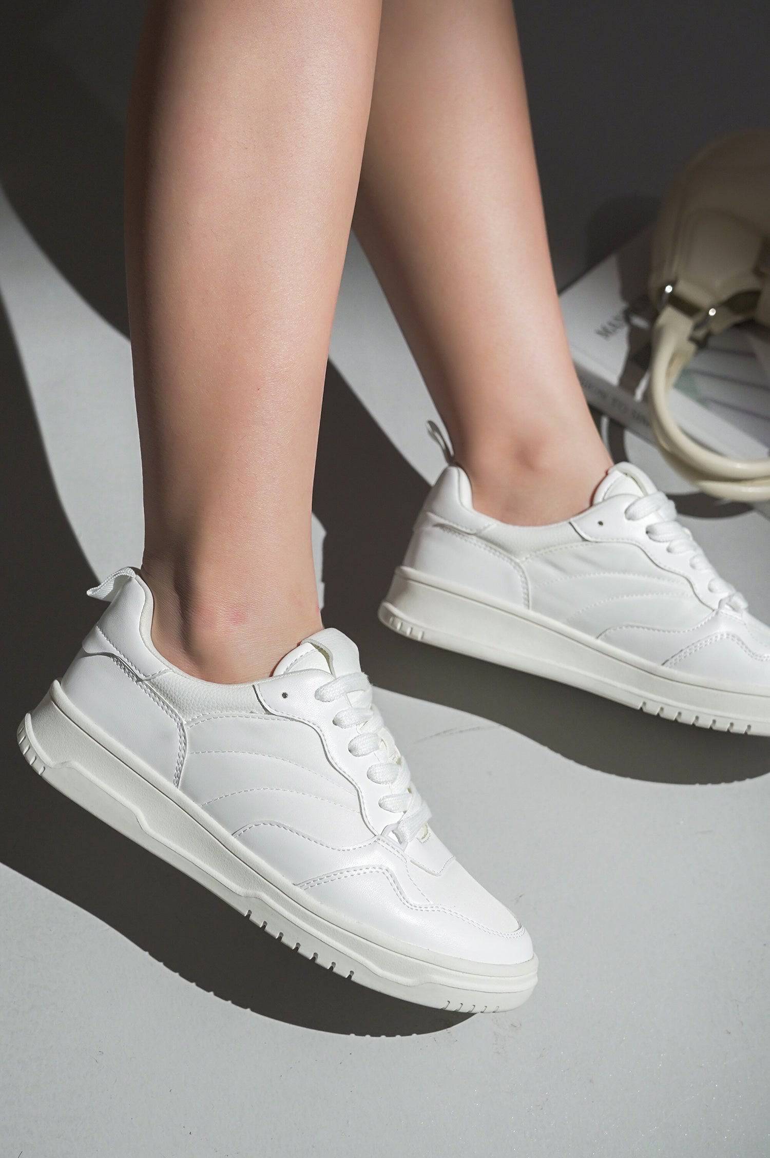 White Kiki vegan leather women's sneakers. Low-top design, lace-up closure, stylish and comfortable.