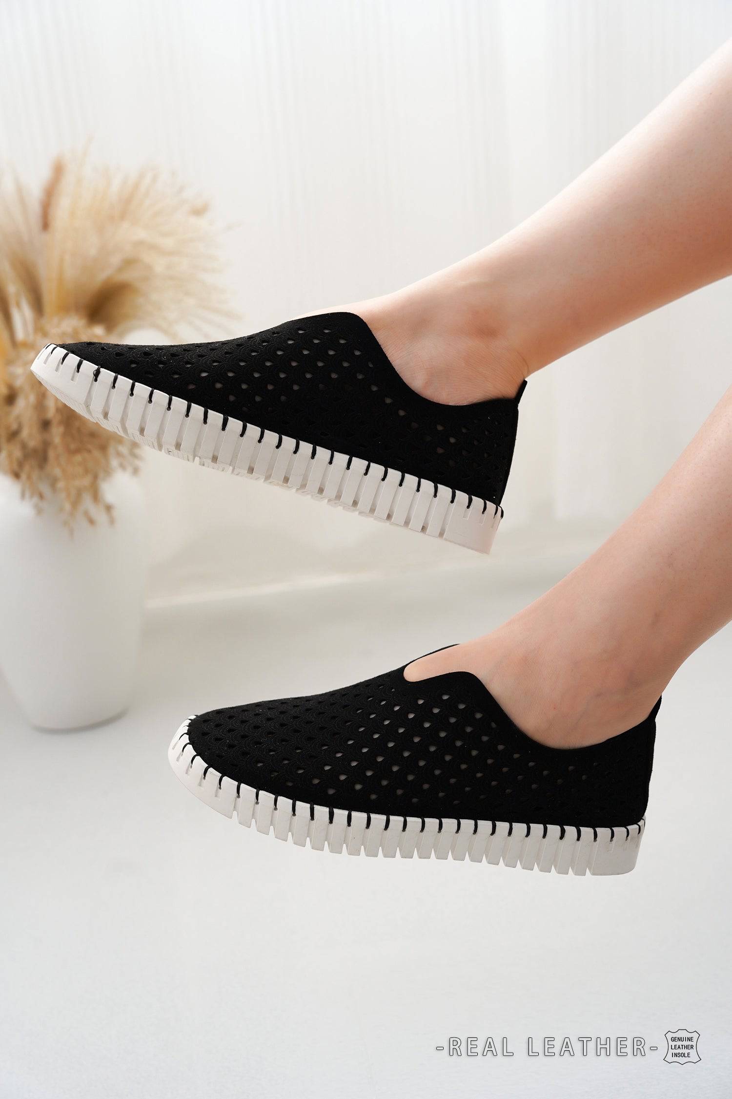 Women's black perforated slip-on loafers with leather insole, white sole. Comfortable, stylish flats.