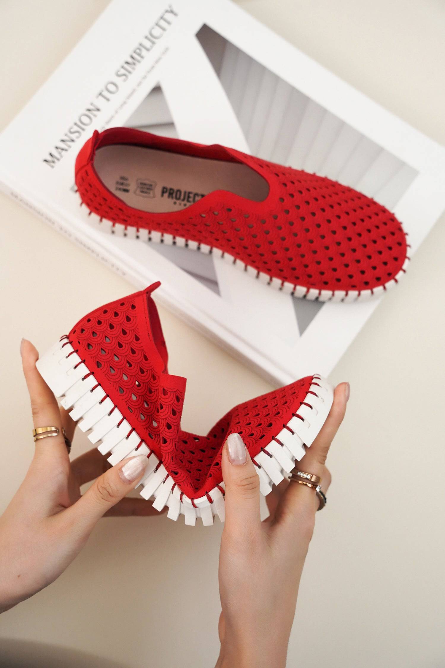 Red perforated slip-on loafers for women, white sole. Flexible design, comfortable flats for travel.