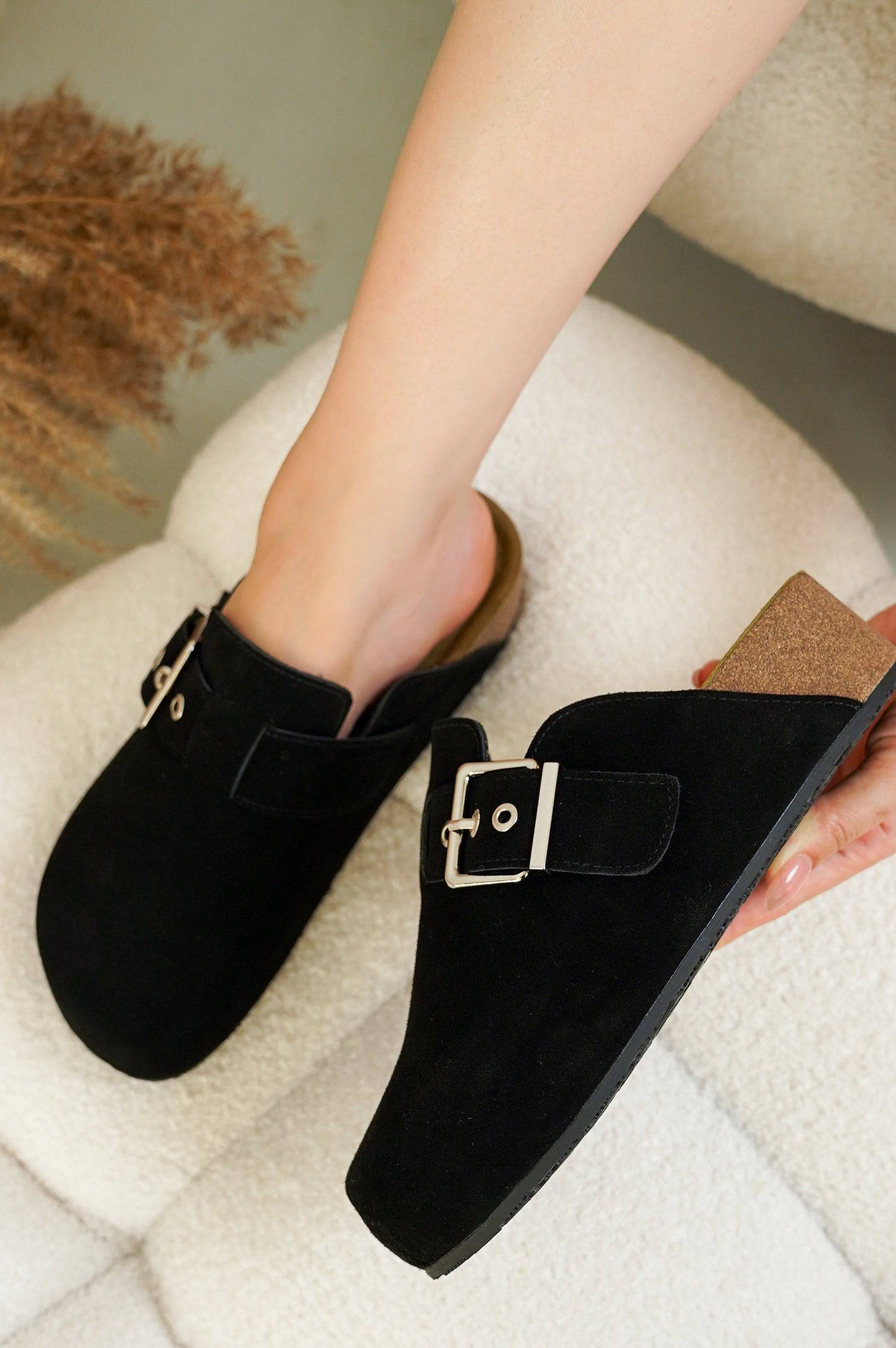 Black Rhona Clogs for Women, featuring suede upper, adjustable buckle, and cork sole detail. Project Cloud comfort.