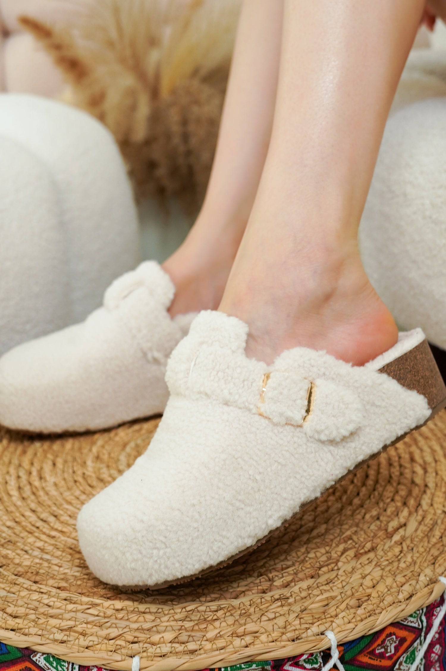 Women's Rhona Clogs in cream shearling, adjustable buckle, on a woven mat. Project Cloud comfort.