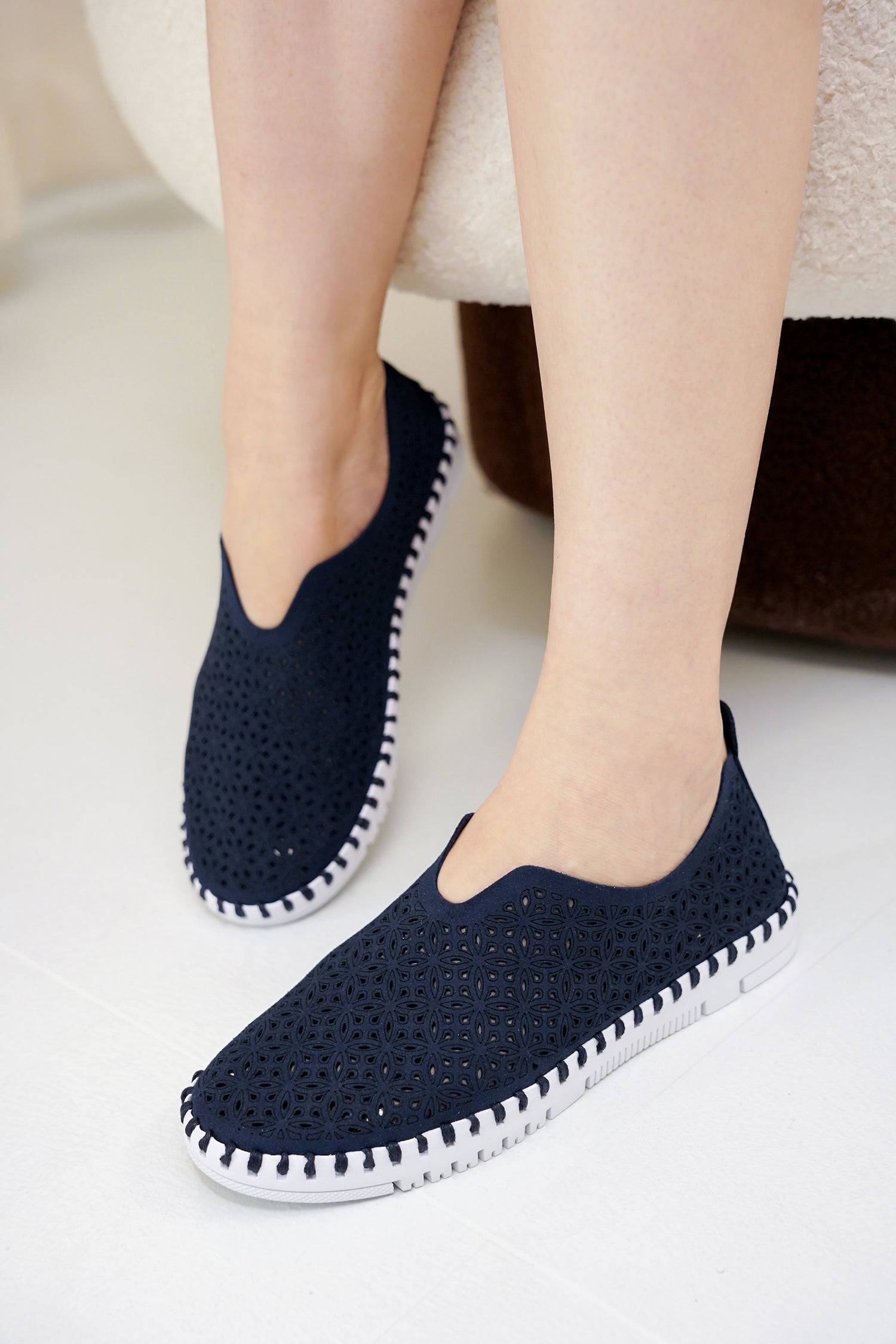 Navy blue slip-on sneakers for women with laser-cut design and white sole. Lightweight, breathable.