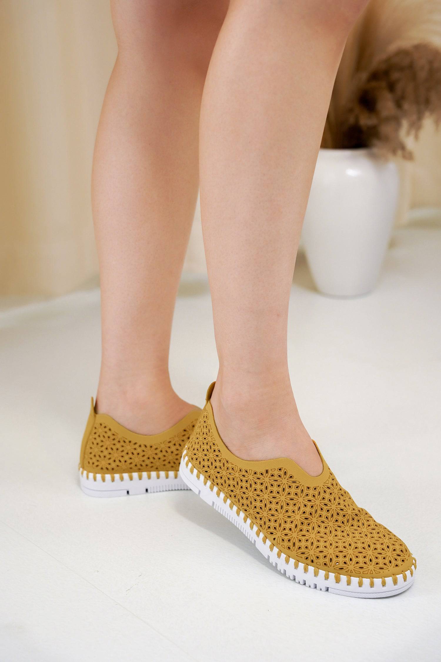 Yellow slip-on sneakers, floral cut design, white sole. Lightweight and comfortable shoes for women.